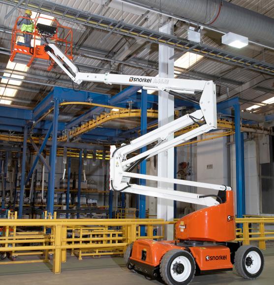 Orange and white boom lift with operator in hi vis vest and yellow hard hat working in industrial facility