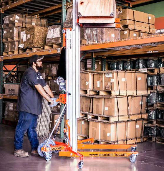 Operator lifting orange and aluminum material lift to height with crate in warehouse