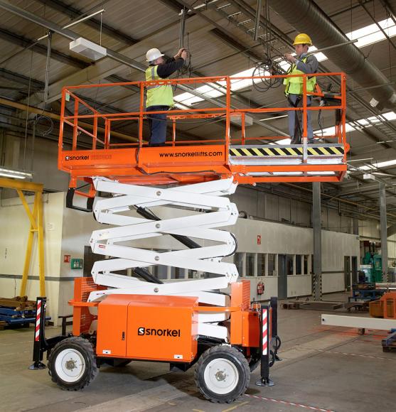 Two operators install wiring stodd in orange and white scissor lift inside factory