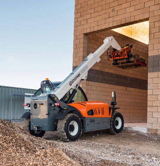 Orange, white and grey telehandler carrying a pallet entering a brick building