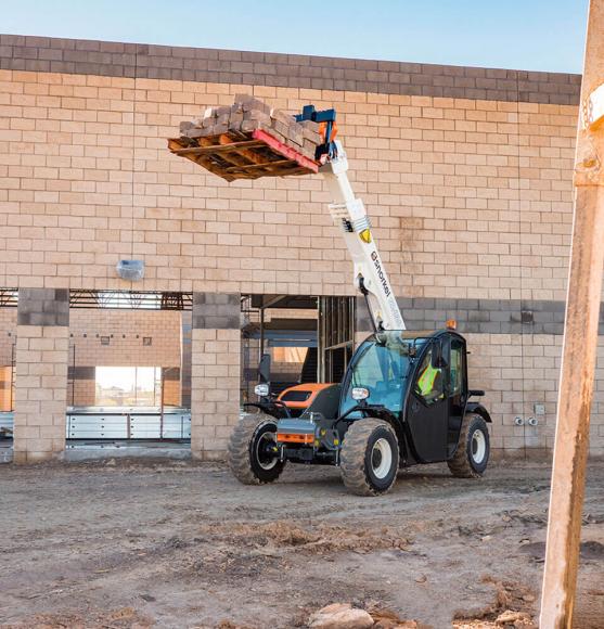 Orange, grey and white telehandler on jobsite lifting pallet of bricks